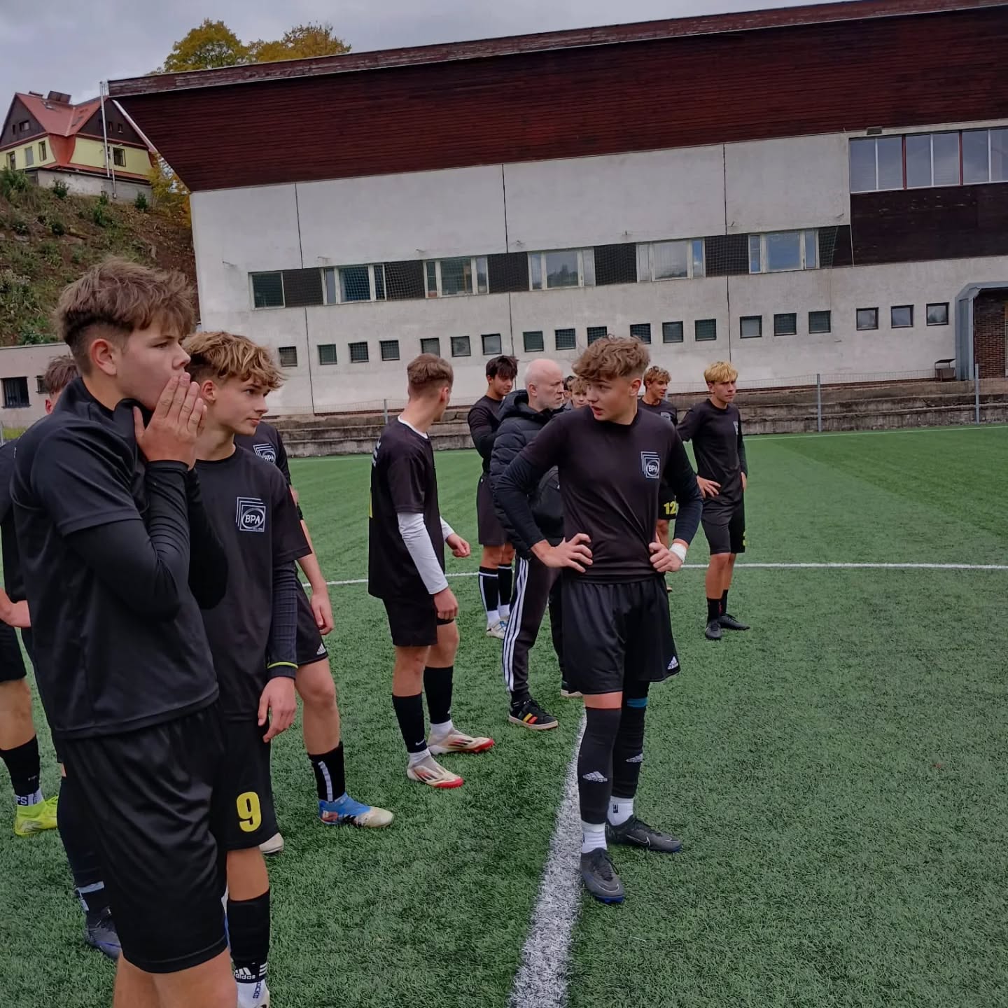 Fotbalisté v černých dresech BPA se semkli na hřišti během utkání.