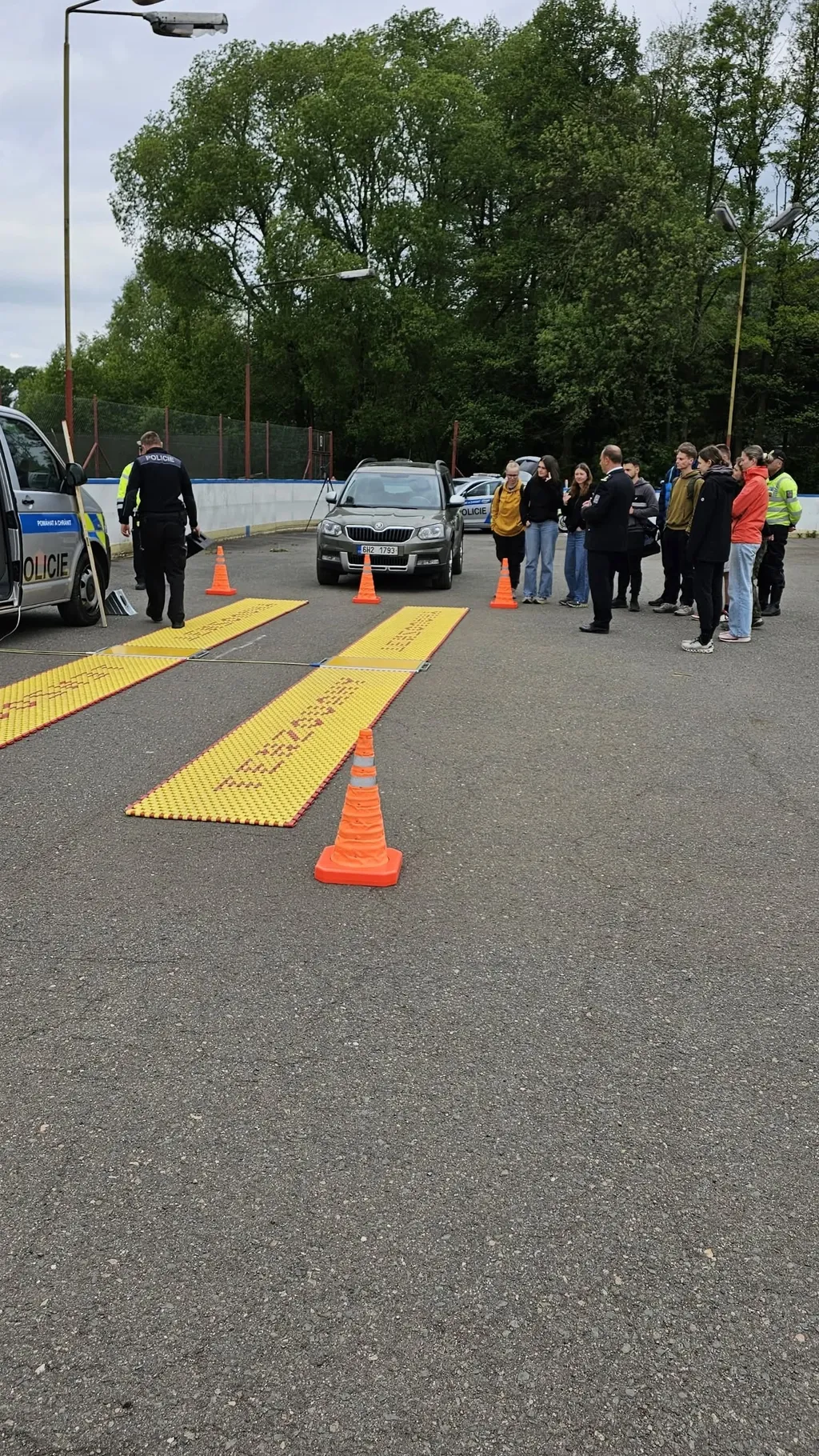Studenti sledují ukázku policejní kontroly vozidla na speciálních detekčních rohožích.