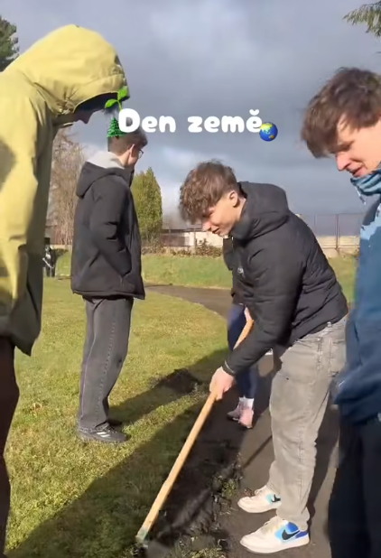 Žáci upravují záhon hráběmi při akci ke Dni Země.