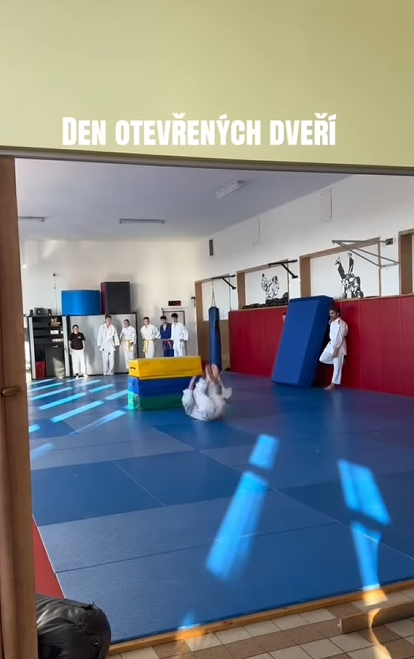 Záběr z tělocvičny s nápisem Den otevřených dveří, kde žáci v kimonech předvádějí bojové umění.