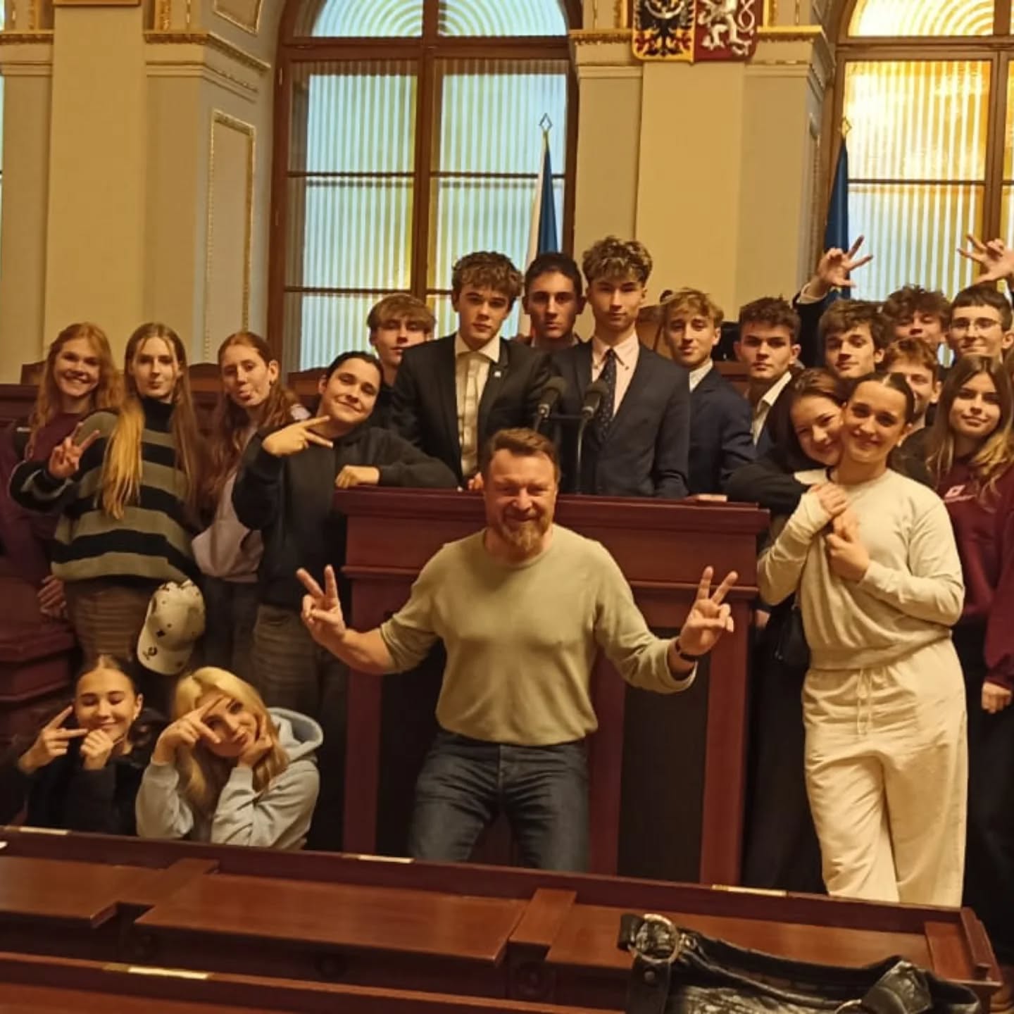 Skupina žáků s doprovodem v jednacím sále Poslanecké sněmovny.